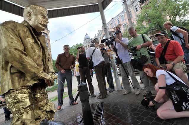 People look at the [Pissing Stalin Golden Monument] created by activists of Ukrainian nationalist party Svoboda in Kiev on May 7, 2012 as art-provocation before V-day celebration