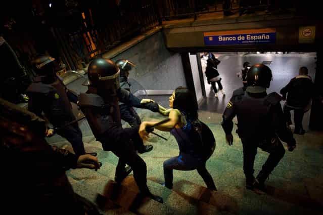 A police officer beats a girl who was taking part in celebrations at Spain's Bank Metro station in Madrid after Real Madrid won the Spanish Soccer League game, May 3, 2012