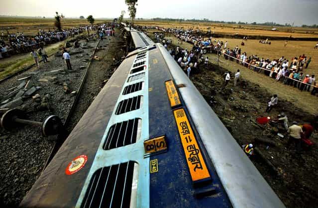 Officials and locals gather around the fallen compartments of Doon Express, a passenger train which derailed in Jaunpur, India on May 31, 2012