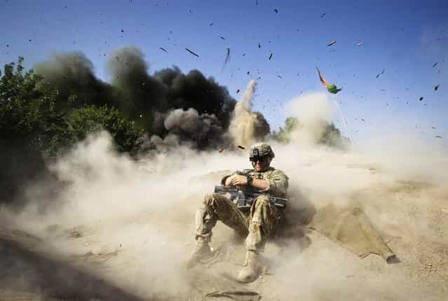 U.S. Army Pvt. Jake Beaudoin takes cover during a controlled detonation to clear an area for setting up a checkpoint, in Zahri district of Kandahar province, southern Afghanistan, May 31
