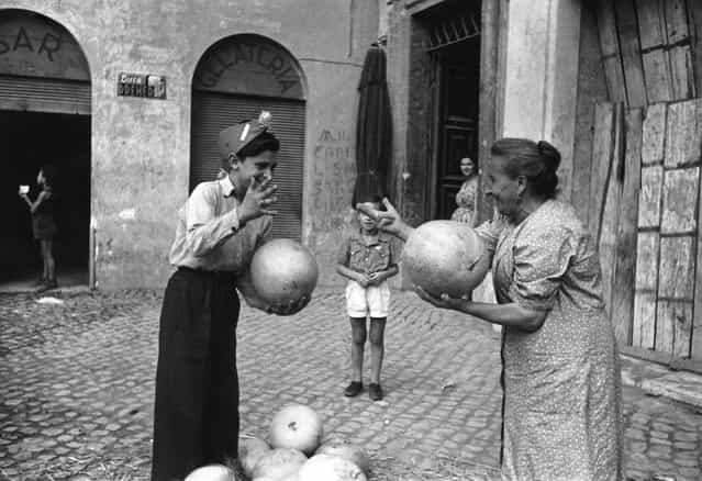 An elderly woman and a boy using hand signs to bargain for canteloupe melons, Italy, 1st November 1947