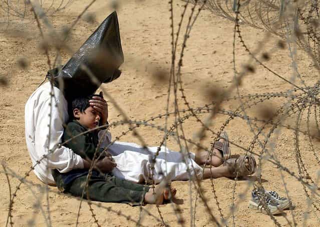 An Iraqi man comforts his 4-year-old son at a regroupment center for POWs of the 101st Airborne Division near An Najaf, Iraq