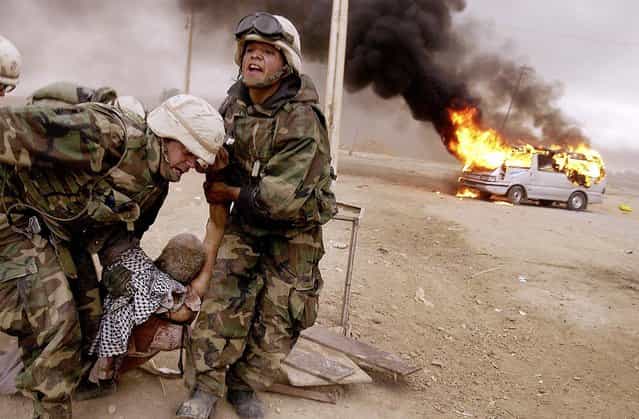 Lt. Jeffrey Goodman, left, and Lance Cpl. Jorge Sanchez drag a wounded civilian away from his burning vehicle during an advance on Baghdad by the 2nd Tank Battalion