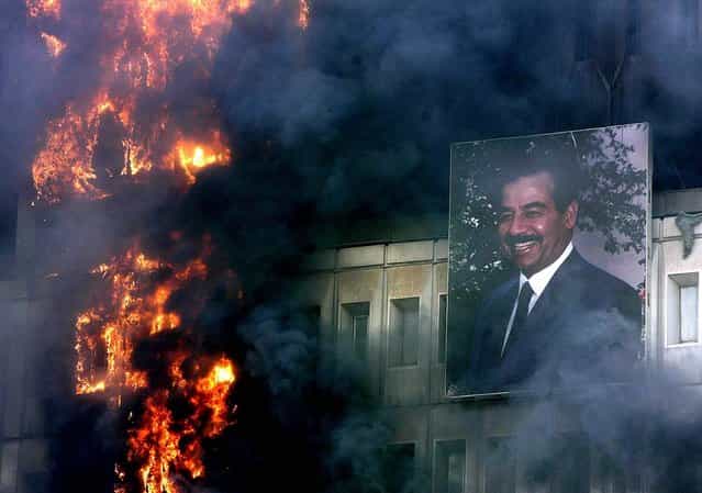 A portrait of Saddam Hussein hangs on the burning Ministry of Transport and Communication building in Baghdad Wednesday, April 9, 2003