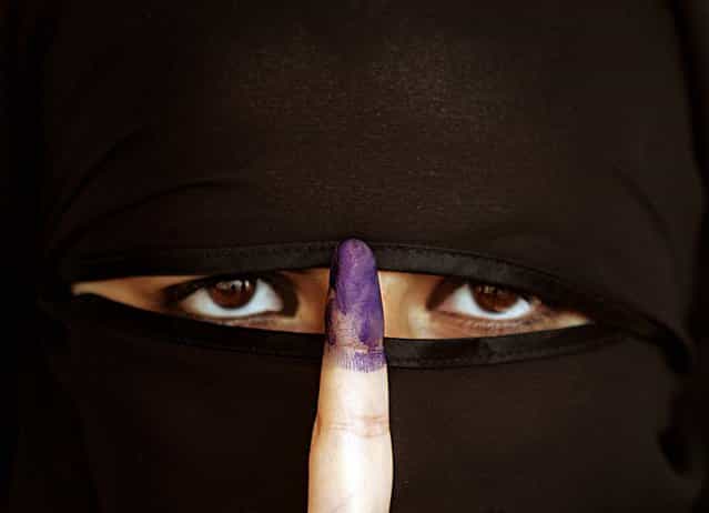 An Iraqi Sunni woman shows her ink-stained finger after casting her vote in Amman December 15, 2005
