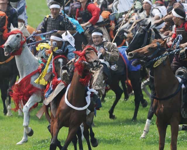 A local man (C) in samurai armor falls off his horse as he tries to catch a yellow sacred flag at the annual Soma Nomaoi Festival in Minamisoma, Fukushima Prefecture, on July 29, 2012. Some 400 horses and thousands of people took part in the 1,000-year-old [Soma Nomaoi], or wild horse chase, at the weekend in the shadow of Japans crippled Fukushima nuclear plant. (Photo by Toru Yamanaka/AFP Photo)