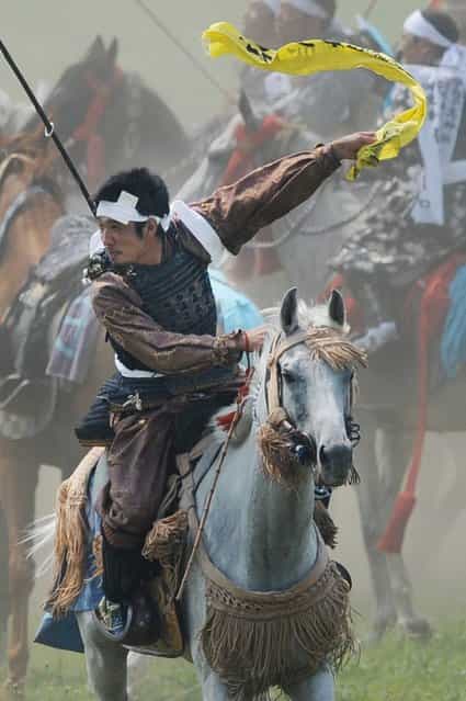 A local man in samurai armor riding his horse waves as he catches a yellow sacred flag at the annual Soma Nomaoi Festival in Minamisoma, Fukushima Prefecture, on July 29, 2012. Some 400 horses and thousands of people took part in the 1,000-year-old [Soma Nomaoi], or wild horse chase, at the weekend in the shadow of Japans crippled Fukushima nuclear plant. (Photo by Toru Yamanaka/AFP Photo)