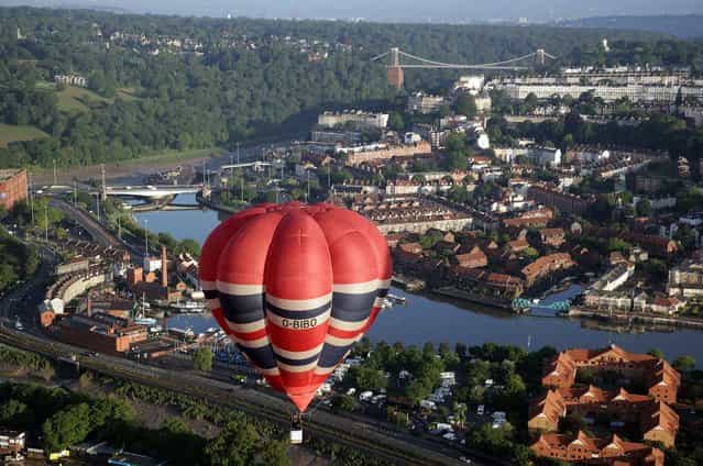Hot air balloons take to the skies over Bristol city centre on August 6, 2012 in Bristol, England. The early morning flight of over twenty balloons over the city was organised as a curtain raiser for the four-day Bristol International Balloon Fiesta which starts on Thursday. Now in its 34th year, the Bristol International Balloon Fiesta is Europes largest annual hot air balloon event in the city that is seen by many balloonists as the home of modern ballooning. (Photo by Matt Cardy)