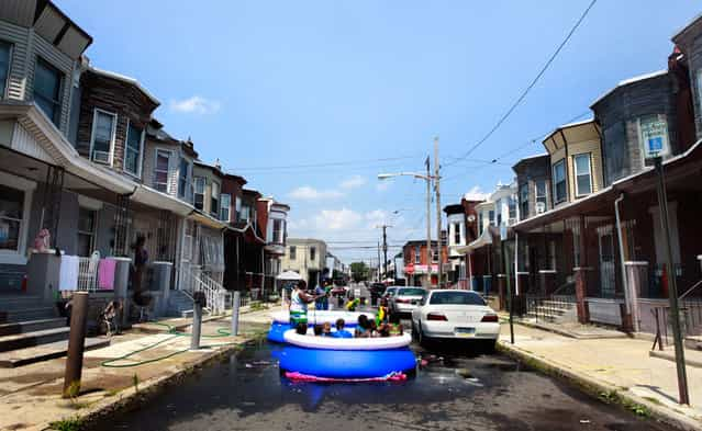 Residents block cars and set up a pool on the street on June 20, 2012, in Philadelphia. Temperatures climbed toward the high 90s along the Eastern Seaboard as an unusually early hot spell heralded the official start of summer. (Photo by Brynn Anderson/AP Photo)