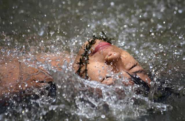 An Indian youth swims in the Dhansari river as she cools off during a hot summer day in Dimapur, India's northeastern state of Nagaland, on May 19, 2012. (Photo by STR/AFP)