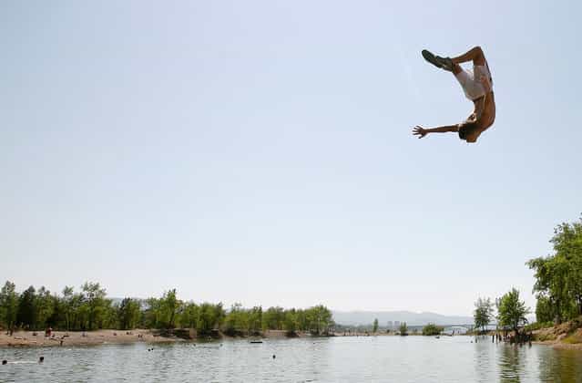 A man jumps into a lake, located on the Tatyshev Island in the middle of the Yenisei River, with the air temperature at about 30 degrees Celsius (86F) in Russia's Siberian city of Krasnoyarsk, on June 14, 2012. (Photo by Ilya Naymushin/Reuters)