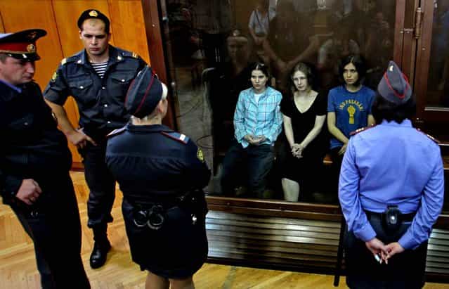 Yekaterina Samutsevich, Maria Alekhina and Nadezhda Tolokonnikova sit behind a glass wall at the court in Moscow. (Photo by Mikhail Metzel/Associated Press)