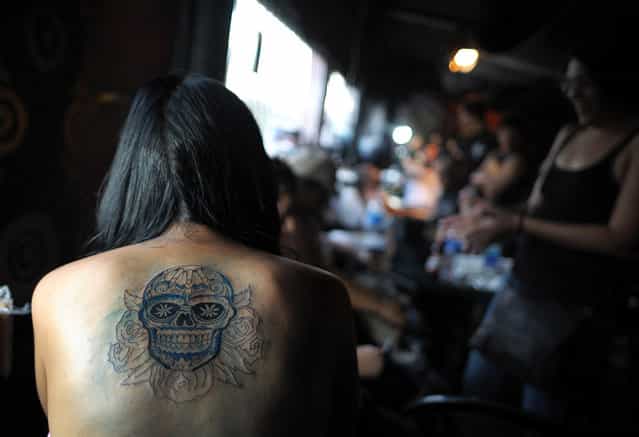 A woman takes a rest as she has her back tattooed during the San Salvador Tattoo Fest in San Salvador, on March 3, 2012. The tattoo festival aimed to promote tattoo art in the rather conservative Salvadorean society. (Photo by Jose Cabezas/AFP)
