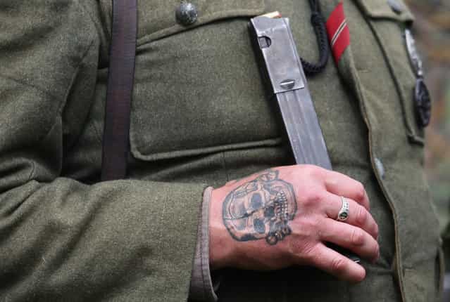 A WWII re-enactor dressed as a German soldier sports an SS Death's Head tattoo as he takes part in a mock battle as part of the two-day Maiden Newton At War 1940s re-enactment weekend in Maiden Newton, near Dorchester, England, on June 23, 2012. The quiet Dorset village of Newton Maiden was seen as a strategic hub during the Second World War and was heavily fortified against a threatened German invasion. It later saw hundreds of American servicemen quartered in the area before the D Day landings. To celebrate the village's wartime past, the biennial event, which started in 2008, has grown into one of the biggest re-enactments in the country and this year featured one of the largest convoys of Second World War vehicles seen in Dorset since D Day in 1944. (Photo by Matt Cardy)