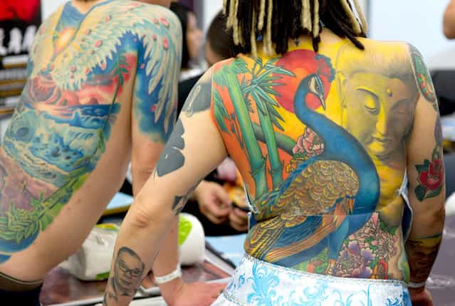 Iris (right) from Taiwan presents her tattoos at the international tattoo convention in Frankfurt am Main, Germany, on March 31, 2012. (Photo by Boris Roessler/AFP)