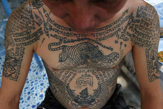 A man shows tattoos on his body at Wat Bang Phra in Nakhon Pathom province, about 80 km (50 miles) from Bangkok, on March 2, 2012. Thousands of believers from across Thailand travel to the monastery to attend the annual tattoo festival to have their bodies adorned with tattoos and to pay their respects to the temple's master tattooist. They believe the tattoos have mystical powers, warding off bad luck and protecting them from harm. (Photo by Sukree Sukplang/Reuters)
