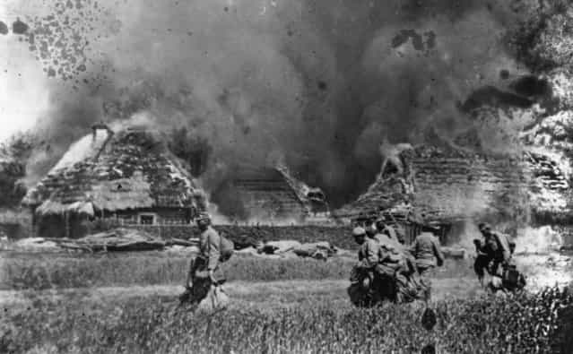 Austrian Infantry passing through a burnt-out village, 1914.