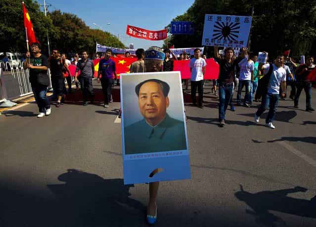 A demonstrator dressed in a traditional costume holds a picture of late Communist leader Mao Zedong during an anti-Japan protest outside the Japanese Embassy in Beijing September 16, 2012. (Photo by Andy Wong/Associated Press)