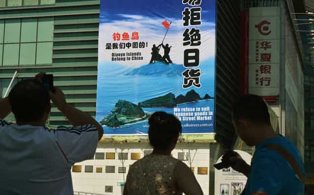 Onlookers view a large protest banner at the Silk Street market, which is famous for selling counterfeit designer brand goods, as anti-Japanese protests continue in Beijing over the Diaoyu/Senkaku Islands issue, on September 17, 2012. (Photo by Mark Ralston/AFP Photo)