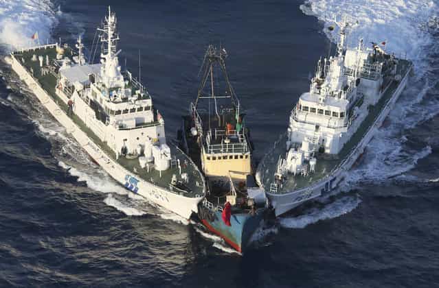 A boat, center, is surrounded by Japan Cost Guard's patrol boats after some activists descended from the boat on Uotsuri Island, one of the islands of Senkaku in Japanese and Diaoyu in Chinese, in East China Sea Wednesday, Aug. 15, 2012. Regional tensions flared on the emotional anniversary of Japan's World War II surrender as activists from China and South Korea used Wednesday's occasion to press rival territorial claims, prompting 14 arrests by Japanese authorities. The 14 people had traveled by boat from Hong Kong to the disputed islands controlled by Japan but also claimed by China and Taiwan. (Photo by Yomiuri Shimbun/Masataka Morita/AP Photo)