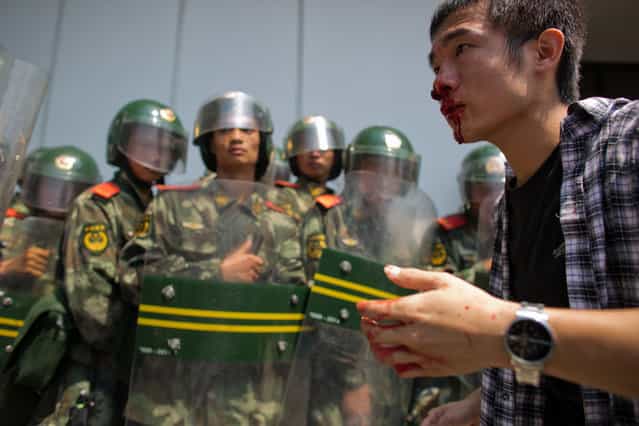 An anti-Japanese protester bleeds from the nose as riot police look on, during a demonstration over the disputed Diaoyu/Senkaku Islands, on September 16, 2012 in Shenzhen, China. (Photo by Lam Yik Fei)