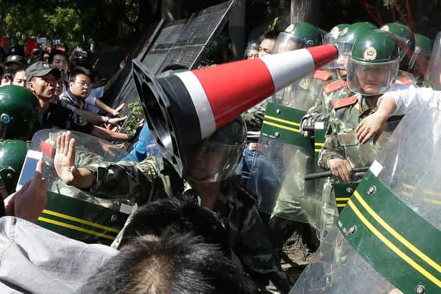 A Chinese paramilitary policeman is hit by a traffic cone as he tries to hold back protesters from storming the Japanese embassy in Beijing, China, on September 15, 2012. (Photo by Ng Han Guan/AP Photo)