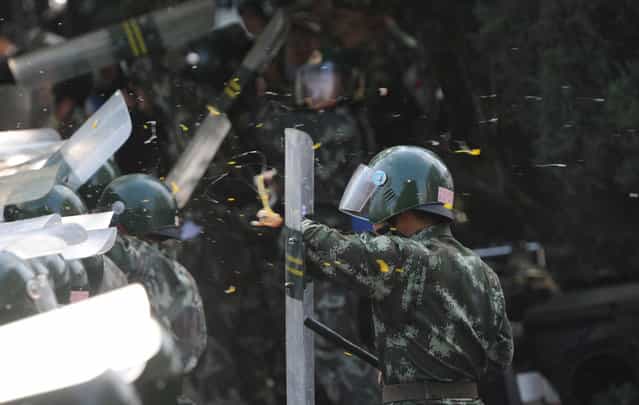 A Chinese riot policeman shields himself from eggs and water bottles thrown by protesters during an anti-Japanese protest outside the Japanese Embassy in Beijing, on September 15, 2012. (Photo by Goh Chai Hin/AFP Photo)