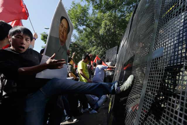 Chinese protesters kick barricades during an anti-Japan protest outside the Japanese embassy in Beijing, on September 15, 2012. (Photo by Ng Han Guan/AP Photo)