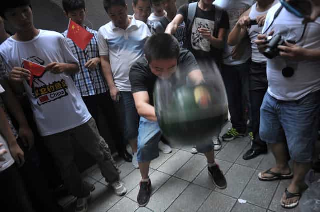 A protester throws a police helmet to the ground as fellow demonstrators take pictures during an anti-Japan protest in Guangzhou, Guangdong province, on September 16, 2012. (Photo by Reuters/Stringer)
