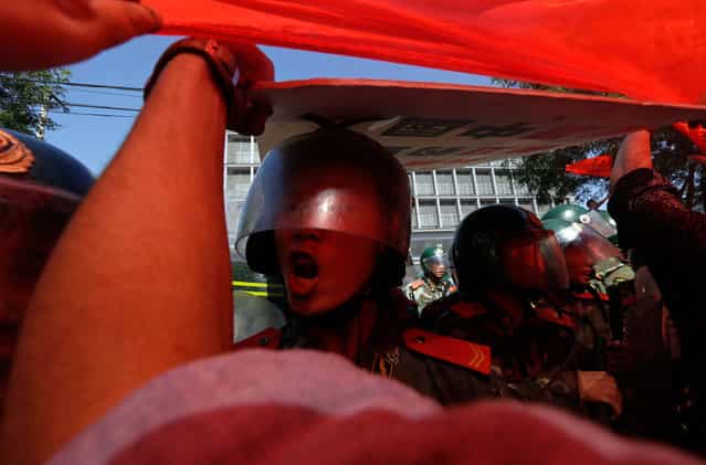 A Chinese paramilitary policeman reacts as a giant Chinese national flag is pulled by protesters towards the Japanese embassy in Beijing, China, on September 15, 2012. (Photo by Ng Han Guan/AP Photo)
