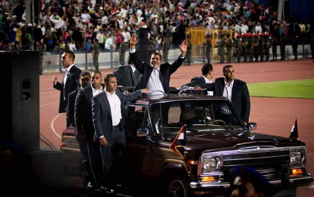 Egyptian President Mohammed Morsi waves upon his arrival in a stadium in Cairo for a speech on the 6th of October national holiday marking the 1973 war with Israel, on October 6, 2012. (Photo by Khalil Hamra/Associated Press)