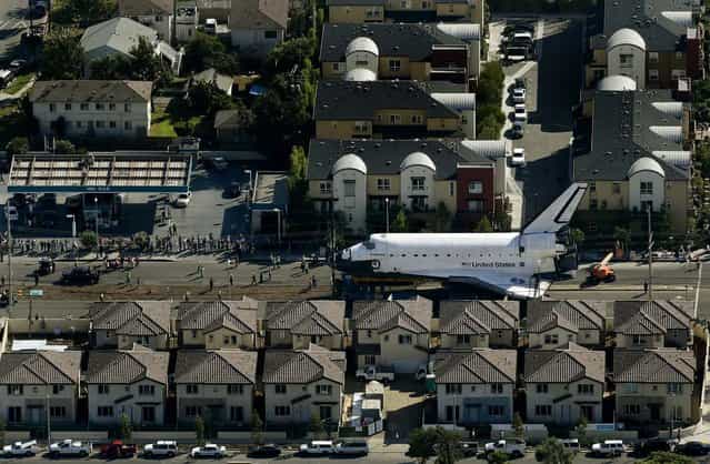 Spectators gather to watch the space shuttle Endeavour make its way down Manchester Blvd. in Los Angeles, on October 12, 2012. Endeavour's 12-mile road trip kicked off shortly before midnight Thursday as it moved from its Los Angeles International Airport hangar en route to the California Science Center, its ultimate destination. (Photo by Chris Carlson/Associated Press)