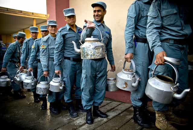 Afghan National Police officers line up with tee pots to get their breakfast at the Police Academy in Kabul, Afghanistan, on October 9, 2012. (Photo by Anja Niedringhaus/Associated Press)