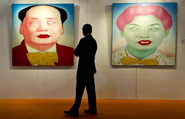 A man looks at two paintings [Mao], and [Chinese Portrait Series No. 12] by Chinese artist Feng Zhengjie during Sotheby's auction press preview in Hong Kong, on October 4, 2012. The paintings are estimated to bring between $32,300 and $45,200. (Photo by Vincent Yu/Associated Press)