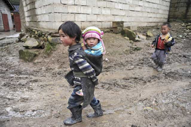 A Yi ethnic minority girl carries her younger sister on her back as she walks amid a muddy road at Butuo county of Liangshan Yi Autonomous Prefecture, Sichuan province, on October 10, 2012. Locked in deep mountains, Liangshan Yi Autonomous Prefecture is the biggest inhabitance region for Chinese Yi minorities, as well as one of the poorest regions in China, according to local media. (Photo by China Daily)