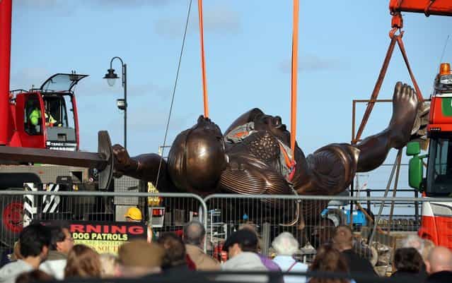 Contractors move Damien Hirst's bronze sculpture of a pregnant woman into positionl on October 16, 2012 in Ilfracombe, England. The bronze-clad, sword-wielding 65ft (20m) statue, named Verity, has been controversially given to the seaside town by the artist, on a 20-year loan and was erected by crane on the pier. (Photo by Matt Cardy)