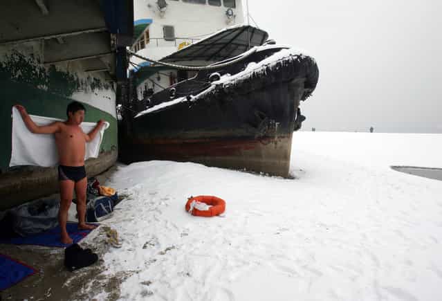 A winter swimmer wipes water on him beside a stranded ship on the beach of the Yangtze River after snow on January 27, 2008 in Wuhan of Hubei Province, China. Measured in Wuhan's Hankou District, the water level of Asia's longest river (about 6,300 km) fell to 13.98 meters, the lowest compared with the same time of year since records began in 1866, affecting shipping, fishery and water supply. (Photo by China Photos)