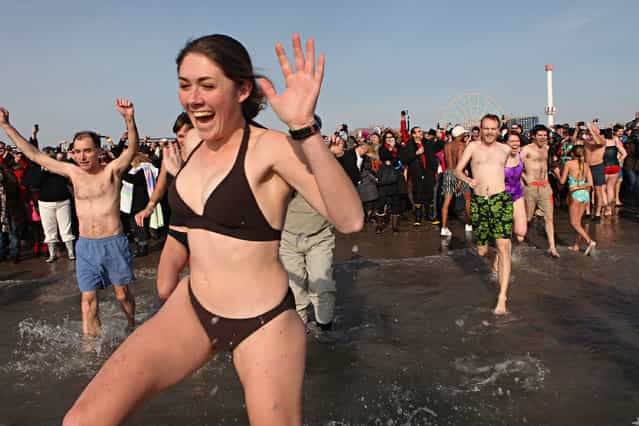 A woman takes part in the annual Coney Island Polar Bear Club New Year's Day swim by running into the ocean at Coney Island on January 1, 2011 in the Brooklyn borough of New York City. The Coney Island Polar Bear Club claims itself as the oldest winter bathing organization in the U.S. and attracts hundreds to the beach for the annual swim in the Atlantic Ocean. (Photo by Andrew Burton)