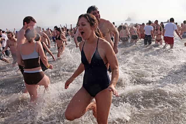 A woman runs out of the ocean after participating in in the annual Coney Island Polar Bear Club New Year's Day swim at Coney Island on January 1, 2011 in the Brooklyn borough of New York City. (Photo by Andrew Burton)