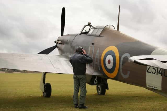 Pilot Dave Harvey checks a Hawker Hurricane Mk XIIa 5711 (G-HURI) fighter aircraft before performing an aerobatic display at the IWM Duxford on October 18, 2012 in Duxford, England. The aeroplane, similar to those that defended British shores during the Battle of Britain in World War II, is due to be auctioned by Bonhams in their sale of [Collectors' Motor Cars and Automobilia] at Mercedes-Benz World Brooklands on December 3, 2012. The plane was built in 1942 and joined the Royal Canadian Air Force the following year, where it remained for the duration of the war, it is expected to fetch up to 17 million GBP. (Photo by Oli Scarff)