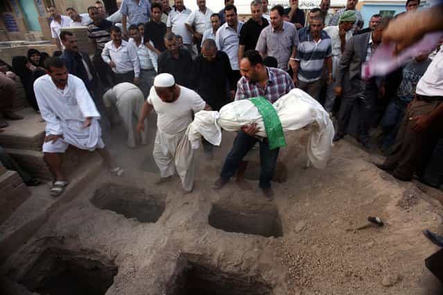 A relative buries Zahra Hadi, 17, in Najaf, 100 miles south of Baghdad, Iraq October 24, 2012. A family of six was killed when a series of attacks struck Shiite neighborhoods in Baghdad early on Tuesday, killing a total of nine people and wounding 26 others, according to Iraqi officials. (Photo by Alaa al-Marjani/Associated Press)