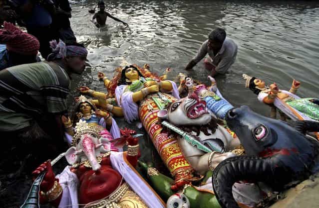 An idol of the Hindu Goddess Durga is immersed into the River Ganges in Kolkata, India October 24, 2012. (Photo by Bikas Das/Associated Press)