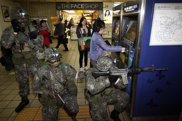 A woman uses a ticket vending machine as South Korean soldiers take part in an anti-terror and security drill at a subway station in Seoul October 25, 2012. (Photo by Kim Hong-Ji/Reuters)