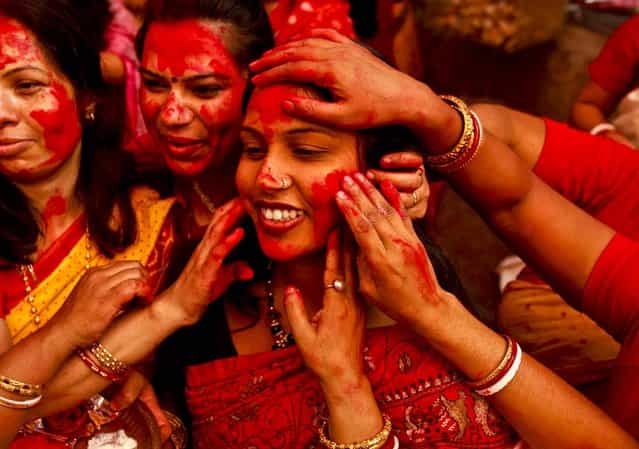 Women apply vermillion powder on each other during Durga Puja festivities in New Delhi, India October 24, 2012. The festival commemorates the slaying of a demon king by lion-riding, ten armed goddess Durga, marking the triumph of good over evil. (Photo by Rajesh Kumar Singh/Associated Press)