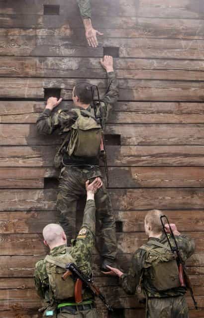 Servicemen from the Interior Ministry special unit climb a wall as they take part in a test near the village of Gorany, some 32 km (20 miles) west of Minsk, October 23, 2012. Servicemen have to pass several tough tests before being awarded entry to the ministry's elite [Red Beret] unit, according to the ministry. (Photo by Vasily Fedosenko/Reuters)