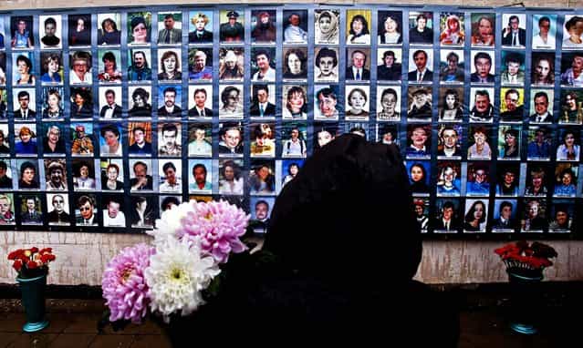 A woman with flowers stands in front of portraits of 130 victims who died in a hostage crisis at a Moscow theater 10 year ago, on October 26, 2012. Chechen militants held 912 audience members for three days. (Photo by Misha Japaridze/Associated Press)