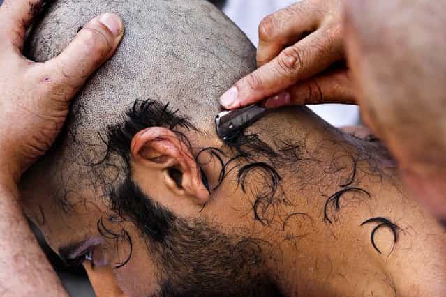 A pilgrim has his head shaved after he cast stones at a pillar, symbolizing the stoning of Satan, in a ritual called [Jamarat], a rite of the annual hajj, the Islamic faith's most holy pilgrimage, in Mina near the Saudi holy city of Mecca, Saudi Arabia October 26, 2012. (Photo by Hassan Ammar/Associated Press)