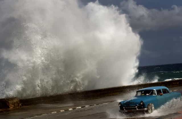 A driver maneuvers his classic American car along a wet road as a wave crashes against the Malecon in Havana, Cuba on Thursday. Hurricane Sandy blasted across eastern Cuba as a potent Category 2 storm and headed for the Bahamas after causing at least two deaths in the Caribbean. (Photo by Ramon Espinosa/Associated Press)