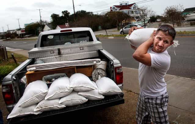 Nick Almeter prepares for the arrival of Hurricane Sandy as he carries sandbags to place by properties along Ocean View Avenue in Norfolk, Virginia on Saturday. (Photo by Ross Taylor/The Virginian-Pilot)