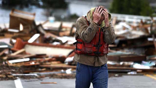 Brian Hajeski, 41, of Brick, N.J., reacts after looking at debris of a home that washed up on to the Mantoloking Bridge Mantoloking, N.J. (Photo by Julio Cortez/Associated Press)